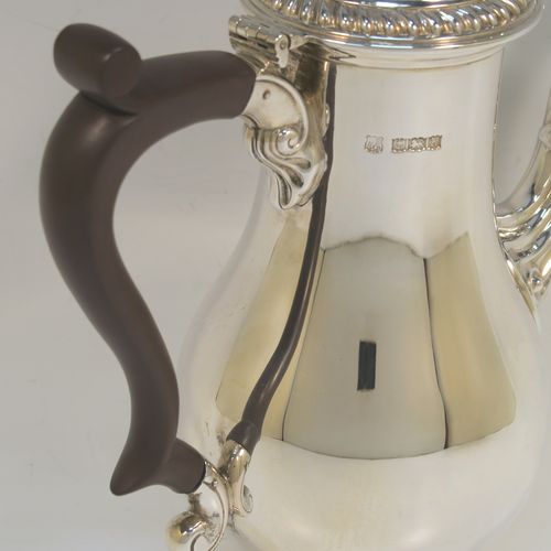 A very handsome Sterling Silver coffee pot in a Georgian style, having a plain round bellied body with applied gadroon borders, a brown wooden scroll handle, a hinged domed lid with a cast pineapple finial, and sitting on a pedestal feet. This beautiful silver coffee pot was made by the Barker Brothers of Birmingham in 1969. The dimensions of this fine hand-made silver coffee pot are height 23 cms (9 inches), length 18.5 cms (7.25 inches), and it weighs approx. 450g (14.5 troy ounces).  