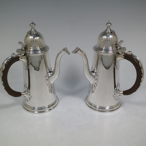 A very unusual and fine pair of Sterling Silver Queen Anne style side-handled coffee or chocolate pots, having plain round bodies with straight tapering sides and applied cut-card work, hinged domed lids with cast thumb-pieces and hinged finials to allow the use of a chocolate stirring spoons, curved spouts with hinged openings, hand-carved wooden scroll handles with applied silver mounts, and all sitting on round collet feet. Made by Heming and Co., of London in 1932. The dimensions of this fine hand-made pair of silver chocoloate or coffee pots are length 16.5 cms (6.5 inches), height 23 cms (9 inches), and they weigh a total of approx. 1,302g (42 troy ounces).   