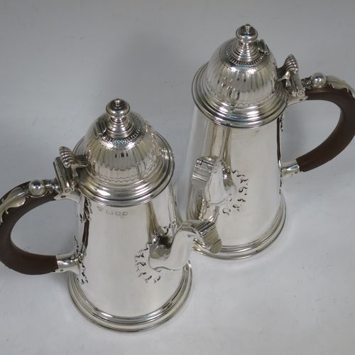 A very unusual and fine pair of Sterling Silver Queen Anne style side-handled coffee or chocolate pots, having plain round bodies with straight tapering sides and applied cut-card work, hinged domed lids with cast thumb-pieces and hinged finials to allow the use of a chocolate stirring spoons, curved spouts with hinged openings, hand-carved wooden scroll handles with applied silver mounts, and all sitting on round collet feet. Made by Heming and Co., of London in 1932. The dimensions of this fine hand-made pair of silver chocoloate or coffee pots are length 16.5 cms (6.5 inches), height 23 cms (9 inches), and they weigh a total of approx. 1,302g (42 troy ounces).   