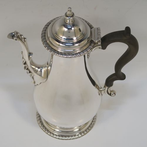 A handsome Antique Edwardian Sterling Silver small coffee pot for two people, having a plain round bellied body with applied gadroon borders, a brown wooden scroll side-handle, a hinged domed lid with cast finial, and all sitting on a pedestal foot. This elegant silver coffee pot was made by Charles Stuart Harris of London in 1906. The dimensions of this fine hand-made antique sterling silver small coffee pot are height 20 cms (8 inches), length 15 cms (6 inches), and it weighs approx. 300g (9.7 troy ounces).   