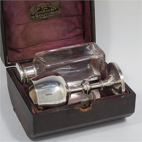 An Antique Victorian Sterling Silver three-piece travelling communion set consisting of chalice, paten, and wine bottle. The chalice having a plain round body with a middle baluster stem, and sitting on a pedestal foot. The paten having a plain round body with a flat border, and sitting on a pedestal foot. The wine bottle having a plain round screw-off corked lid, and the glass body with hand-cut panelled decoration. All three pieces sit in their original purple satin and velvet-lined presentation box. Made by Horace Woodward and Co., of Birmingham in 1882. The dimensions of this fine hand-made antique silver travelling communion set are height of chalice 9 cms (3.5 inches), diameter of paten 7 cms (2.75 inches), height of bottle 10 cms (4 inches), and with a total weight of approx. 93g (3 troy ounces). Please note that the interior material lining is stained, there is damage to the wooden box where the clasp is, and there is a contemporaneous inscription underneath the paten.   