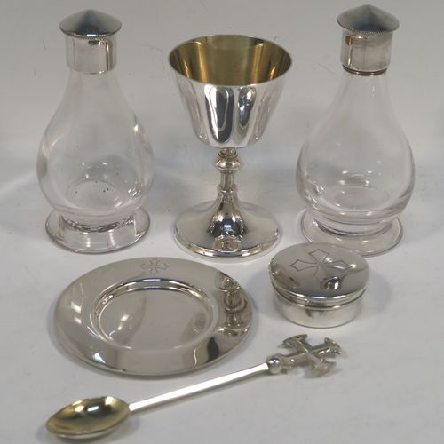 An elegant and complete Sterling Silver six-piece travelling communion set consisting of chalice, paten, water, and wine bottles, a wafer pyx box, and an anointing spoon. The chalice having a plain round body with tapering sides, a gold-gilt interior, and sitting on a round pedestal foot. The paten and pyx box having plain round bodies. The wine and water bottles having plain round screw-off lids, cork seals, and hand-cut crystal bodies. All sitting in their original dark blue satin and velvet-lined presentation box with secure catches and carrying handle (the lid having an extra folding compartment). This beautiful communion set was all made by Wippell Mowbray Church Furnishers Ltd., of London in 1972. The dimensions of this fine hand-made silver travelling communion set are height of chalice 9 cms (3.5 inches), diameter of paten 8.5 cms (3.3 inches), and with a total weight of approx. 200g (6.5 troy ounces).