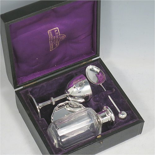 A Sterling Silver four-piece travelling communion set consisting of chalice, paten, spoon, and wine bottle. The chalice having a plain round body, a gold-gilt interior, and sitting on a hexagonal pedestal foot. The paten having a hexagonal body with an applied shaped border, and sitting on a collet foot. The wine bottle having a plain round screw-off lid, a cork seal, and the glass body with hand-cut panelled decoration. The anointing spoon having a plain oval bowl and ball finial. Both the chalice and paten are engraved with a Christogram. All sitting in its original purple satin and velvet-lined presentation box. Made by A. R. Mowbray & Co. Ltd., of London in 1930. The dimensions of this fine hand-made silver travelling communion set are height of chalice 8 cms (3.25 inches), diameter of paten 5.5 cms (2.25 inches), length of spoon 10 cms (4 inches), and with a total weight of approx. 125g (4 troy ounces).    