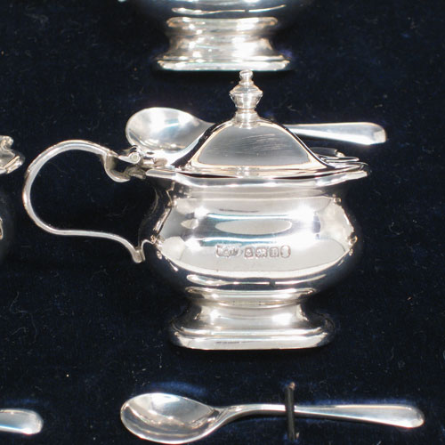 Sterling silver six-piece baluster condiment set in original satin and velvet-lined presentation box, having two open salts and two covered mustard pots all with blue-glass liners, two pepper pots, and four silver condiment spoons. Made by mappin and Webb of Birmingham in 1935. Height of pepper pots 8 cms (3 inches), length of mustard pots 7 cms (2.75 inches). Total weight approx. 232g (7.5 troy ounces).    