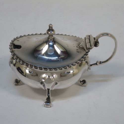 A handsome and large Antique Edwardian Sterling Silver seven-piece condiment service, consisting of a mustard pot with hinged lid and blue-glass liner, four salt cellars with blue-glass liners, and two pepper pots with pull-off lids, all with scroll fluted bellied bodies and sitting four scroll feet, and all fitted into their original dark blue satin and velvet-lined red presentation box. Made by James Round of London  in 1903. The dimensions of this fine hand-made condiment service are height of pepper pot 9 cms (3.5 inches), length of mustard pot 9 cms (3.5 inches), and with a total weight of approx. 353g (11.4 troy ounces).   