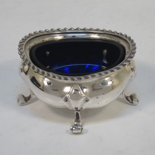 A handsome and large Antique Edwardian Sterling Silver seven-piece condiment service, consisting of a mustard pot with hinged lid and blue-glass liner, four salt cellars with blue-glass liners, and two pepper pots with pull-off lids, all with scroll fluted bellied bodies and sitting four scroll feet, and all fitted into their original dark blue satin and velvet-lined red presentation box. Made by James Round of London  in 1903. The dimensions of this fine hand-made condiment service are height of pepper pot 9 cms (3.5 inches), length of mustard pot 9 cms (3.5 inches), and with a total weight of approx. 353g (11.4 troy ounces).   