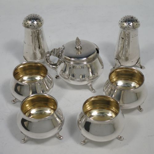 A pretty Antique Edwardian Sterling Silver seven-piece condiment service, having plain round bellied bodies, with gold-gilt linings for the salt cellars, pull-off lids on the peppers, a hinged lid on the mustard pot and original blue-glass liner, together with five condiment spoons, and all in their original dark green velvet and cream satin-lined presentation box. Consisting of one mustard pot, two pepper pots, four salt cellars, and five condiment spoons. All made by Charles Edwards of London in 1904 (apart from the mustard spoon which is hallmarked for 1934). The dimensions of this fine hand-made silver condiment set are height of peppers 6 cms (2.3 inches), length of mustard 6 cms (2.3 inches), and with a total weight of approx. 235g (7.6 troy ounces).    