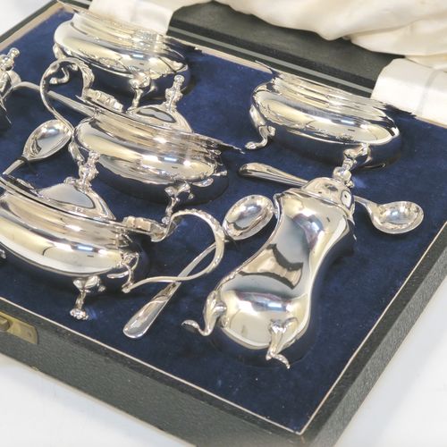 A handsome and large Antique Edwardian Silver Plated six-piece condiment service in a Chippendale style, consisting of two mustard pots with hinged lids and blue-glass liners, two salt cellars with blue-glass liners, two pepper pots with pull-off lids, all with bellied bodies and sitting on four scroll feet, together with two salt spoons and two mustard spoons, and all fitted into their original cream satin and and dark blue velvet-lined presentation box. This beautiful antique silver-plated condiment service was made by Walker and Hall of Sheffield in ca. 1910. The dimensions of this fine hand-made antique condiment service are height of pepper pots 10 cms (4 inches), length of mustard pots 10 cms (4 inches), and length of salt cellars 7.5 cms (3 inches).  