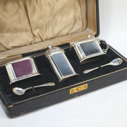 A very elegant Sterling Silver three-piece condiment set in an Art Deco style with straight-sided panelled bodies, consisting of an open salt cellar with a blue glass liner, a pepper pot with pull-off lid, a mustard pot with blue glass liner and hinged lid, together with two condiment spoons, and all in their cream satin and black velvet-lined presentation box. All made by Selfridges and Co., of Birmingham in 1939, apart from the spoons which are hallmarked for Birmingham in 1972. The dimensions of this fine hand-made silver condiment service are length of mustard pot 7 cms (2.75 inches), height of pepper pot 7.5 cms (3 inches), length of salt cellar 5 cms (3 inches), and with a total weight of approx. 118g (3.8 troy ounces).   