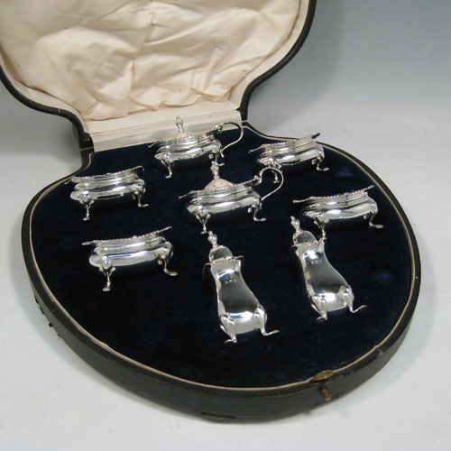 Sterling silver eight-piece condiment set, consisting of four open salt cellars with blue-glass liners, two mustard pots with hinged lids, and two pepper shakers, all with plain baluster bodies, gadroon borders, and sitting on four foliate feet, and all fitted into an original satin and velvet-lined presentation box. Made by E. S. Barnsley & Co., of Birmingham in 1918. The dimensions of this fine hand-made silver condiment service are height of pepper pots 8 cms (3 inches), length of mustard pots 8 cms (3 inches), and with a total weight of approx. 255g (8.2 troy ounces).