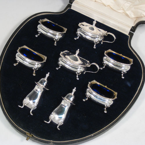 Sterling silver eight-piece condiment set, consisting of four open salt cellars with blue-glass liners, two mustard pots with hinged lids, and two pepper shakers, all with plain baluster bodies, gadroon borders, and sitting on four foliate feet, and all fitted into an original satin and velvet-lined presentation box. Made by E. S. Barnsley & Co., of Birmingham in 1918. The dimensions of this fine hand-made silver condiment service are height of pepper pots 8 cms (3 inches), length of mustard pots 8 cms (3 inches), and with a total weight of approx. 255g (8.2 troy ounces).