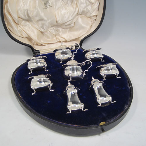 Antique sterling silver eight-piece condiment set, consisting of four open salt cellars with blue-glass liners, two mustard pots with hinged lids, and two pepper shakers, all with plain baluster round bodies, chippendale borders, and sitting on four cabriole legs, and all fitted into an original satin and velvet-lined presentation box. Made by Robert and William Sorely pf London in 1911. The dimensions of this fine hand-made silver condiment service are height of pepper pots 7 cms (2.75 inches), length of mustard pots 7 cms (2.75 inches), and with a total weight of approx. 252g (8 troy ounces). 
