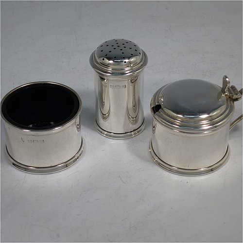 A Sterling Silver three-piece condiment set, in a very plain round Georgian style with applied reeded borders, and consisting of a pepper pot, open salt cellar, and covered mustard pot, the latter two items with original blue glass liners, and all in their original cream satin and black velvet-lined presentation box. Made by J. B Chatterley & Sons Ltd., of Birmingham in 1940. The dimensions of this fine hand-made silver condiment service are height of pepper pot 5.5 cms (2.25 inches), length of mustard pot 6.5 cms (2.5 inches), and the total weight is approx. 93g (3 troy ounces).   