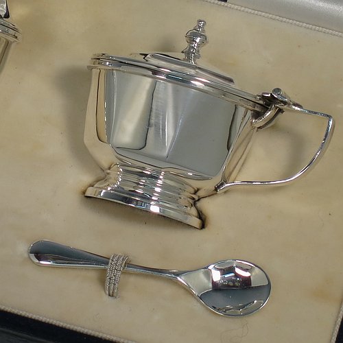 A Sterling Silver three-piece condiment set, in a panelled Art Deco style, and consisting of a pepper pot, open salt cellar, and covered mustard pot, the latter two items with original blue glass liners, and sitting on pedestal feet, the pepper pot with a pull-off lid with finial, and together with two silver condiment spoons, and all in their original cream satin & velvet-line presentation box. Made by Mappin & Webb of Birmingham in 1930 (the spoons being made in 1902). The dimensions of this fine hand-made silver condiment service are height of pepper pot 7 cms (2.75 inches), length of mustard pot 6.5 cms (2.5 inches), and the total weight is approx. 89g (2.9 troy ounces).    