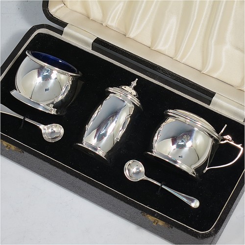 A Sterling Silver three-piece condiment set, in a very plain round bellied style, and consisting of two condiment spoons, a pepper pot, open salt cellar, and covered mustard pot, the latter two items with original blue glass liners, and all in their original cream satin and black velvet-lined presentation box. Made by Israel Sigmund Greenberg of Birmingham in 1939. The dimensions of this fine hand-made silver condiment service are height of pepper pot 7 cms (2.75 inches), length of mustard pot 7 cms (2.75 inches), and the total weight is approx. 88g (2.8 troy ounces).    