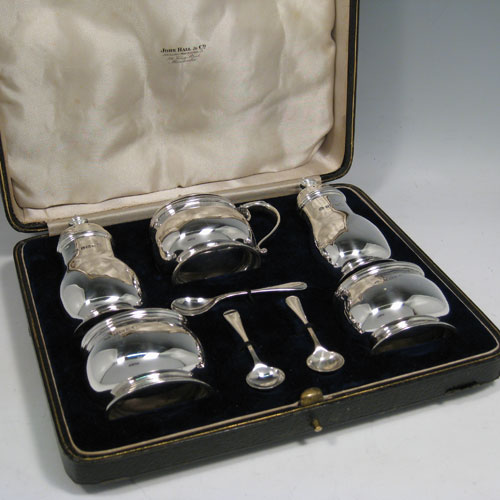    Sterling silver condiment service, consisting of a mustard pot with hinged lid and blue glass liner, two salt cellars with blue glass liners, two pepper pots with pull-off lids, all with plain baluster bodies sitting on collet feet, together with their original condiment spoons, and all fitted into their original satin and velvet-lined presentation box. Made by the Adies Brothers of Birmingham in 1935. Height of pepper pot 10 cms (4 inches), length of mustard pot 9 cms (3.5 inches). Total weight approx. 395g (12.7 troy ounces).