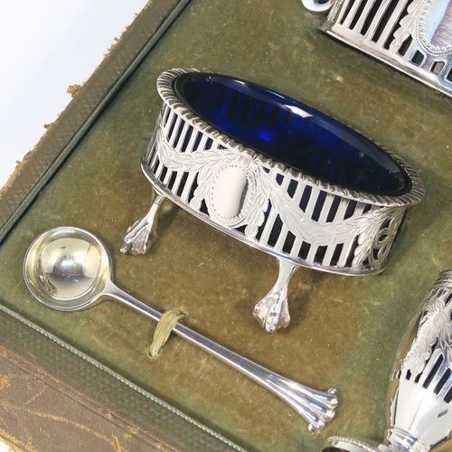 A large and heavy Antique Sterling Silver six-piece condiment service in a Neoclassical style with hand-pierced and laurel-leaf swags decoration, all with interior blue glass liners, and claw and ball feet. Consisting of two mustard pots with domed hinged lids, two salt cellars, two pepper pots with bayonet fit lids, and together with their original condiment spoons in the Onslow pattern, and all fitted into their original light green satin and velvet-lined presentation box. This beautiful condiment service was made by Goldsmiths and Silversmiths of London in 1925 to 1929. The dimensions of this fine hand-made antique silver condiment service are height of pepper pots 6.5 cms (2.5 inches), length of mustard pots 9 cms (3.5 inches), and with a total weight of approx. 327g (10.5 troy ounces).   