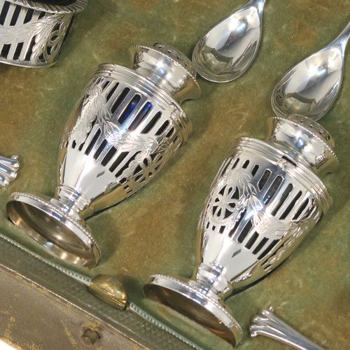 A large and heavy Antique Sterling Silver six-piece condiment service in a Neoclassical style with hand-pierced and laurel-leaf swags decoration, all with interior blue glass liners, and claw and ball feet. Consisting of two mustard pots with domed hinged lids, two salt cellars, two pepper pots with bayonet fit lids, and together with their original condiment spoons in the Onslow pattern, and all fitted into their original light green satin and velvet-lined presentation box. This beautiful condiment service was made by Goldsmiths and Silversmiths of London in 1925 to 1929. The dimensions of this fine hand-made antique silver condiment service are height of pepper pots 6.5 cms (2.5 inches), length of mustard pots 9 cms (3.5 inches), and with a total weight of approx. 327g (10.5 troy ounces).   