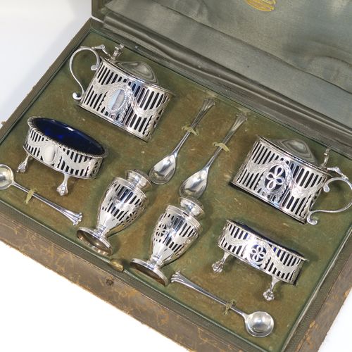 A large and heavy Antique Sterling Silver six-piece condiment service in a Neoclassical style with hand-pierced and laurel-leaf swags decoration, all with interior blue glass liners, and claw and ball feet. Consisting of two mustard pots with domed hinged lids, two salt cellars, two pepper pots with bayonet fit lids, and together with their original condiment spoons in the Onslow pattern, and all fitted into their original light green satin and velvet-lined presentation box. This beautiful condiment service was made by Goldsmiths and Silversmiths of London in 1925 to 1929. The dimensions of this fine hand-made antique silver condiment service are height of pepper pots 6.5 cms (2.5 inches), length of mustard pots 9 cms (3.5 inches), and with a total weight of approx. 327g (10.5 troy ounces).   