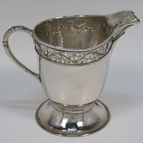 A beautiful Sterling Silver Arts and Crafts style cream or milk jug, having a round body with hand-hammered decoration, with an applied and hand-chased top band of floral work, with a cast rounded side-handle, and all sitting on a spreading round pedestal foot with applied rope-twist borders. This fantastic silver milk or cream jug was made by Harold Edwin Landon of Chester in 1933. The dimensions of this fine hand-made Arts and Crafts jug are height 11.5 cms (4.5 inches), length 14 cms (5.5 inches), and with a weight of approx. 195g (6.3 troy ounces).  