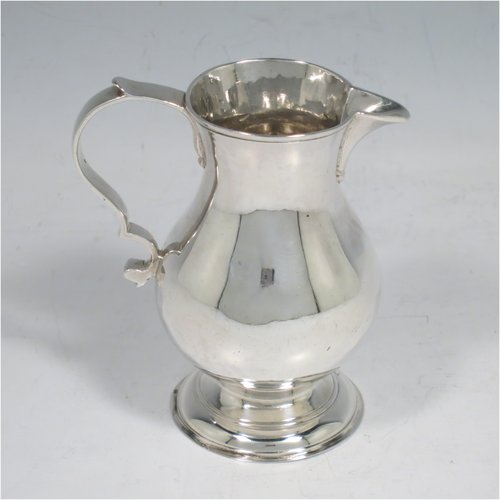 An Antique Georgian Sterling Silver cream jug, in the sparrow-beak style, having a round baluster body, scroll handle, and sitting on a collet foot. Made by George Hindmarsh of London in 1749. The dimensions of this fine hand-made antique silver cream jug are height 9 cms (3.5 inches), length 8 cms (3 inches), and it weighs approx. 82g (2.6 troy ounces).