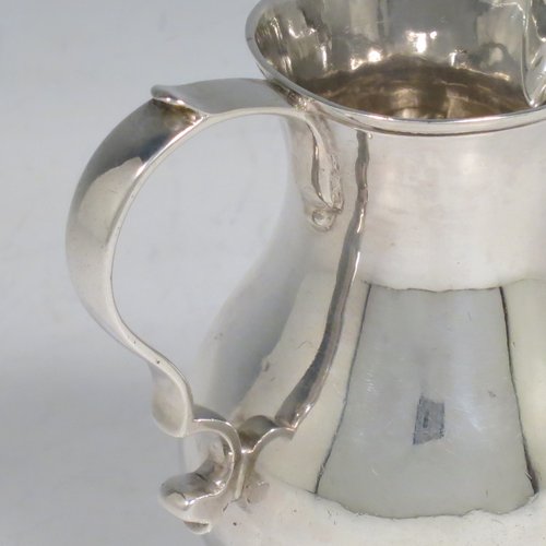 An Antique Georgian Sterling Silver cream jug, in the sparrow-beak style, having a round baluster body, scroll handle, and sitting on a collet foot. Made by George Hindmarsh of London in 1749. The dimensions of this fine hand-made antique silver cream jug are height 9 cms (3.5 inches), length 8 cms (3 inches), and it weighs approx. 82g (2.6 troy ounces).