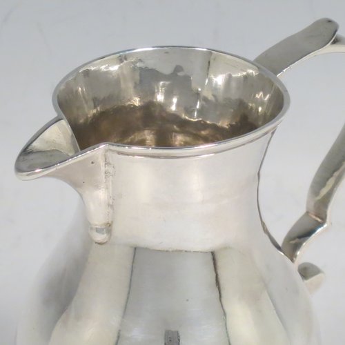 An Antique Georgian Sterling Silver cream jug, in the sparrow-beak style, having a round baluster body, scroll handle, and sitting on a collet foot. Made by George Hindmarsh of London in 1749. The dimensions of this fine hand-made antique silver cream jug are height 9 cms (3.5 inches), length 8 cms (3 inches), and it weighs approx. 82g (2.6 troy ounces).