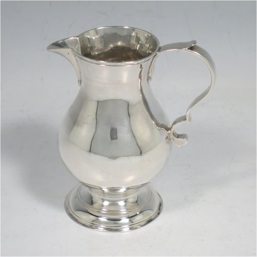 An Antique Georgian Sterling Silver cream jug, in the sparrow-beak style, having a round baluster body, scroll handle, and sitting on a collet foot. Made by George Hindmarsh of London in 1749. The dimensions of this fine hand-made antique silver cream jug are height 9 cms (3.5 inches), length 8 cms (3 inches), and it weighs approx. 82g (2.6 troy ounces).