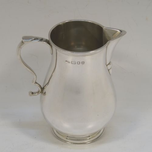 A large and handsome Sterling Silver cream jug, in a George I Sparrow-Beak style with a plain round bellied body, an applied reeded top border, a scroll handle with an anthemion thumb-piece, a sparrow-beak spout, and sitting on a collet foot. This beautiful cream jug was made by Alfred Ernest Neighbour of London in 1937. The dimensions of this fine hand-made and large silver cream jug are height 10.5 cms (4.25 inches), length 10 cms (4 inches), and it weighs approx. 181g (5.8 troy ounces).  