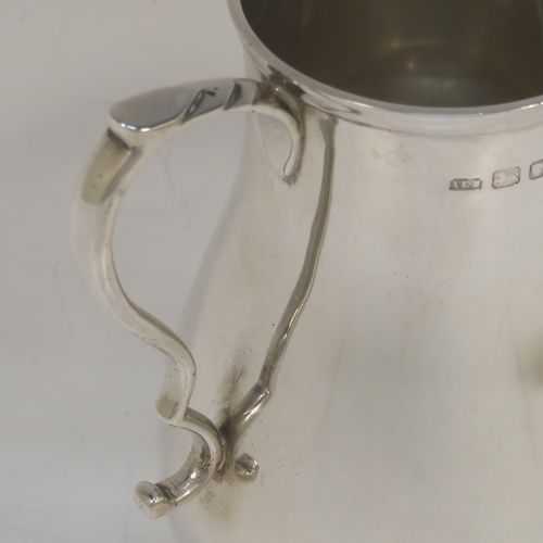 A large and handsome Sterling Silver cream jug, in a George I Sparrow-Beak style with a plain round bellied body, an applied reeded top border, a scroll handle with an anthemion thumb-piece, a sparrow-beak spout, and sitting on a collet foot. This beautiful cream jug was made by Alfred Ernest Neighbour of London in 1937. The dimensions of this fine hand-made and large silver cream jug are height 10.5 cms (4.25 inches), length 10 cms (4 inches), and it weighs approx. 181g (5.8 troy ounces).  