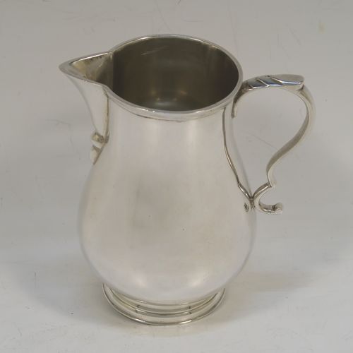 A large and handsome Sterling Silver cream jug, in a George I Sparrow-Beak style with a plain round bellied body, an applied reeded top border, a scroll handle with an anthemion thumb-piece, a sparrow-beak spout, and sitting on a collet foot. This beautiful cream jug was made by Alfred Ernest Neighbour of London in 1937. The dimensions of this fine hand-made and large silver cream jug are height 10.5 cms (4.25 inches), length 10 cms (4 inches), and it weighs approx. 181g (5.8 troy ounces).  