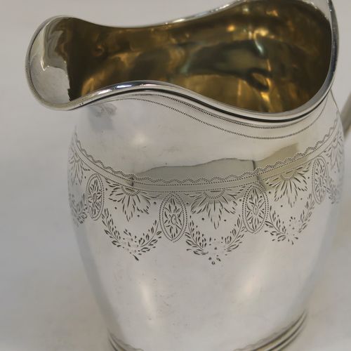 A pretty Antique Victorian Sterling Silver cream jug, having a round bellied body with hand-engraved  floral decoration, an applied reeded border and reeded scroll handle, all sitting on a flat base. This beautiful antique silver cream or milk jug was made in London in 1890. The dimensions of this fine hand-made antique silver cream jug are height 9 cms (3.5 inches), length 11 cms (4.25 inches), and it weighs approx. 82g (2.6 troy ounces).  