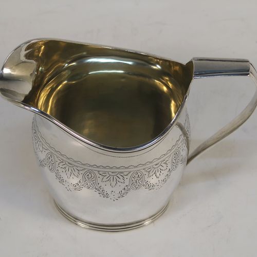 A pretty Antique Victorian Sterling Silver cream jug, having a round bellied body with hand-engraved  floral decoration, an applied reeded border and reeded scroll handle, all sitting on a flat base. This beautiful antique silver cream or milk jug was made in London in 1890. The dimensions of this fine hand-made antique silver cream jug are height 9 cms (3.5 inches), length 11 cms (4.25 inches), and it weighs approx. 82g (2.6 troy ounces).  