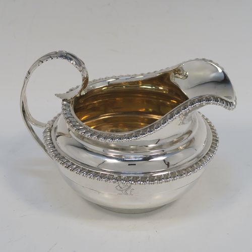 A very handsome Antique Georgian Sterling Silver large cream jug, having a plain round bellied body with applied gadroon borders, a scroll handle with floral thumb-piece, a gold-gilt interior, and all sitting on a round collet foot. This elegant silver milk or cream jug was made by the Emes and Barnard of London in 1820. The dimensions of this fine hand-made antique silver cream jug are height 10 cms (4 inches), length 14 cms (5.5 inches), and it weighs approx. 247g (8 troy ounces).  