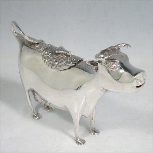 An Antique Victorian Sterling Silver Dutch Cow cream jug, in a George II Cow creamer style, having a hinged lid with hand-chased flowers and an applied model of a bee, with a handle made from from the cows looped tail, and a spout made from the cows mouth, all sitting on four hoof feet. Made in ca. 1880 with Dutch hallmarks. The dimensions of this fine hand-made silver cow creamer are length 14.5 cms (5.75 inches), height 10 cms (4 inches), and it weighs approx. 126g (4 troy ounces).   