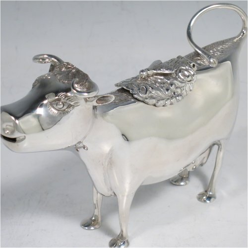 An Antique Victorian Sterling Silver Dutch Cow cream jug, in a George II Cow creamer style, having a hinged lid with hand-chased flowers and an applied model of a bee, with a handle made from from the cows looped tail, and a spout made from the cows mouth, all sitting on four hoof feet. Made in ca. 1880 with Dutch hallmarks. The dimensions of this fine hand-made silver cow creamer are length 14.5 cms (5.75 inches), height 10 cms (4 inches), and it weighs approx. 126g (4 troy ounces).   