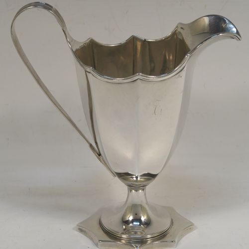 A very handsome Antique Georgian Sterling Silver cream jug, having a plain panelled octagonal body with tapering sides in a Helmet style, a reeded scroll handle and applied top border, and sitting on a pedestal foot with an octagonal shaped base. This beautiful silver cream jug was made by Henry Chawner of London in 1787. The dimensions of this fine hand-made antique silver cream jug are length 13 cms (5 inches), height 14.5 cms (5.75 inches), and it weighs approx. 153g (4.9 troy ounces). Please note that this item is crested.  