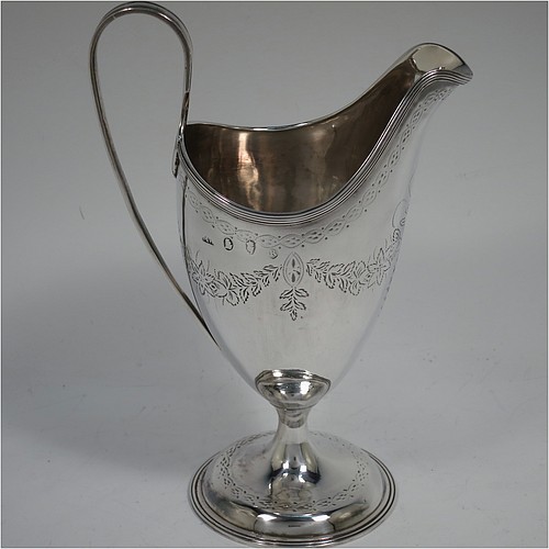 A very pretty Irish Antique Georgian Sterling Silver cream jug, having a round body with tapering sides in a Helmet style, with hand-engraved swags of floral decoration, a vacant oval cartouche, an applied reeded border, a scroll handle, and sitting on a pedestal foot with a round base. Made by Matthew West of Dublin in 1789. The dimensions of this fine hand-made antique Irish silver cream jug are length 11.5 cms (4.5 inches), height 16 cms (6.25 inches), and it weighs approx. 178g (5.7 troy ounces).