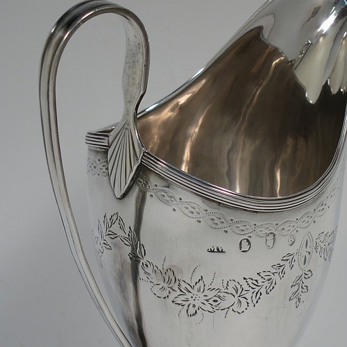 A very pretty Irish Antique Georgian Sterling Silver cream jug, having a round body with tapering sides in a Helmet style, with hand-engraved swags of floral decoration, a vacant oval cartouche, an applied reeded border, a scroll handle, and sitting on a pedestal foot with a round base. Made by Matthew West of Dublin in 1789. The dimensions of this fine hand-made antique Irish silver cream jug are length 11.5 cms (4.5 inches), height 16 cms (6.25 inches), and it weighs approx. 178g (5.7 troy ounces).