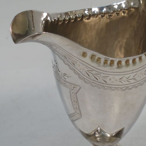 A pretty Antique Georgian Sterling Silver cream jug, having a round body with tapering sides in a Helmet style, with an upper band of floral decoration, a vacant front cartouche, a hand-punched bead border, a scroll handle, and sitting on a pedestal foot with a square base. Made by Peter and Anne Bateman of London in 1792. The dimensions of this fine hand-made antique silver cream jug are length 10 cms (4 inches), height 13 cms (5 inches), and it weighs approx. 84g (2.7 troy ounces).   