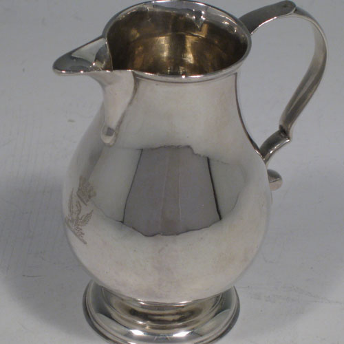 An Antique Georgian Sterling Silver cream jug, in the sparrow-beak style, having a round baluster body, scroll handle, and sitting on a collet foot. Made in the George II period and hallmarked for London in 1729. The dimensions of this fine hand-made antique silver cream jug are height 9 cms (3.5 inches), length 8 cms (3 inches), and it weighs approx. 95g (3.1 troy ounces). Please note that this item is crested.