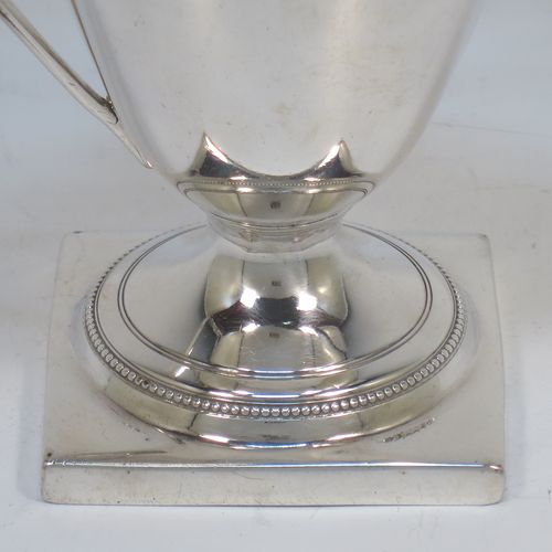 A very elegant Antique Georgian Sterling Silver cream jug, having a round body with tapering sides in a Helmet style, an applied bead-edged border, a reeded scroll handle, and sitting on a pedestal foot with a square base. Made in London in 1790. The dimensions of this fine hand-made antique silver cream jug are length 12 cms (4.75 inches), height 13 cms (5 inches), and it weighs approx. 117g (3.8 troy ounces). Please note that this item is crested.   