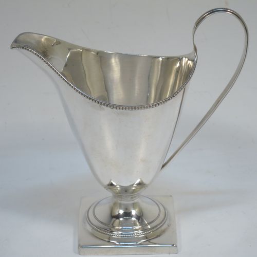 A very elegant Antique Georgian Sterling Silver cream jug, having a round body with tapering sides in a Helmet style, an applied bead-edged border, a reeded scroll handle, and sitting on a pedestal foot with a square base. Made in London in 1790. The dimensions of this fine hand-made antique silver cream jug are length 12 cms (4.75 inches), height 13 cms (5 inches), and it weighs approx. 117g (3.8 troy ounces). Please note that this item is crested.   