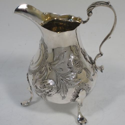 A very pretty Antique early Victorian Sterling Silver cream or milk jug having a round bellied body with hand-chased floral decoration surrounding a vacant cartouche, a scroll handle with anthemion leaf thumb-piece, a shaped border with a spout, a gold-gilt interior, and sitting on three cast trefoil feet. Made by William Hunter of London in 1845. The dimensions of this fine hand-made antique silver cream jug are height 11.5 cms (4.5 inches), length 10 cms (4 inches), and it weighs approx. 115g (3.7 troy ounces).    