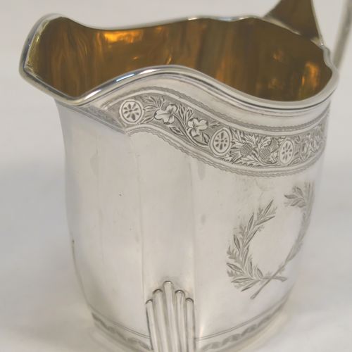 A very pretty Antique Victorian Sterling Silver milk or cream jug, having a panelled oval mainly straight-sided body, with hand-engraved bands of floral decoration, and hand-chased half-fluted corners, a gold-gilt interior, an applied reeded border, a scroll handle with flat top, and sitting on a flat base. This beautiful antique silver cream or milk jug was made by J. B. Carrington of London in 1887. The dimensions of this fine hand-made antique silver jug are height 10 cms (4 inches), length 12.5 cms (5 inches), and it weighs approx. 137g (4.4 troy ounces).  