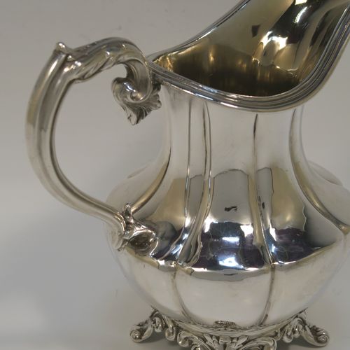 A very pretty and large Antique early Victorian Sterling Silver milk or cream jug, having a round body with hand-chased melon fluting, an applied reeded top border, a scroll handle with anthemion leaf thumb-piece, a gold-gilt interior, and all sitting on four cast foliate feet. This beautiful silver milk jug was made by Hayne and Cater of London in 1837. The dimensions of this fine hand-made antique silver cream jug are height 14 cms (4.5 inches), length 15 cms (6 inches), and it weighs approx. 237g (7.6 troy ounces).  