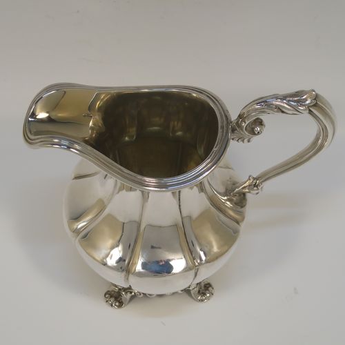 A very pretty and large Antique early Victorian Sterling Silver milk or cream jug, having a round body with hand-chased melon fluting, an applied reeded top border, a scroll handle with anthemion leaf thumb-piece, a gold-gilt interior, and all sitting on four cast foliate feet. This beautiful silver milk jug was made by Hayne and Cater of London in 1837. The dimensions of this fine hand-made antique silver cream jug are height 14 cms (4.5 inches), length 15 cms (6 inches), and it weighs approx. 237g (7.6 troy ounces).  