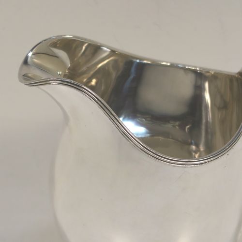 A very elegant Sterling Silver cream jug, having a plain oval bellied body, an applied reeded border and reeded scroll handle, and all sitting on a flat base. This handsome silver cream jug was made by A. Marston and Co., of Birmingham in 1933. The dimensions of this fine hand-made sterling silver cream jug are height 11 cms (4.25 inches), length 12 cms (4.75 inches), and it weighs approx. 164g (5.3 troy ounces). 