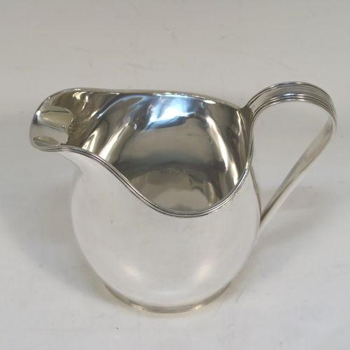 A very elegant Sterling Silver cream jug, having a plain oval bellied body, an applied reeded border and reeded scroll handle, and all sitting on a flat base. This handsome silver cream jug was made by A. Marston and Co., of Birmingham in 1933. The dimensions of this fine hand-made sterling silver cream jug are height 11 cms (4.25 inches), length 12 cms (4.75 inches), and it weighs approx. 164g (5.3 troy ounces). 