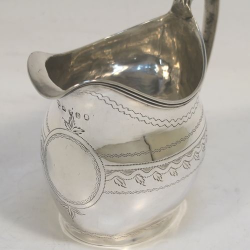 A very pretty Antique Georgian Sterling Silver cream jug, having a round bellied body with hand-engraved bands of stipple and floral work, an applied reeded border and reeded scroll handle, and all sitting on a flat base. This elegant antique silver cream jug was made by Urquart and Hart of London in 1786. The dimensions of this fine hand-made antique silver cream jug are height  cms (3.75 inches), length 11 cms (4.3 inches), and it weighs approx. 78g (2.5 troy ounces).   